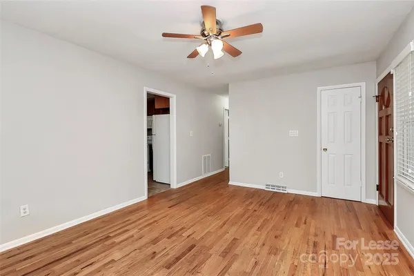 an empty room with wooden floor and a ceiling fan