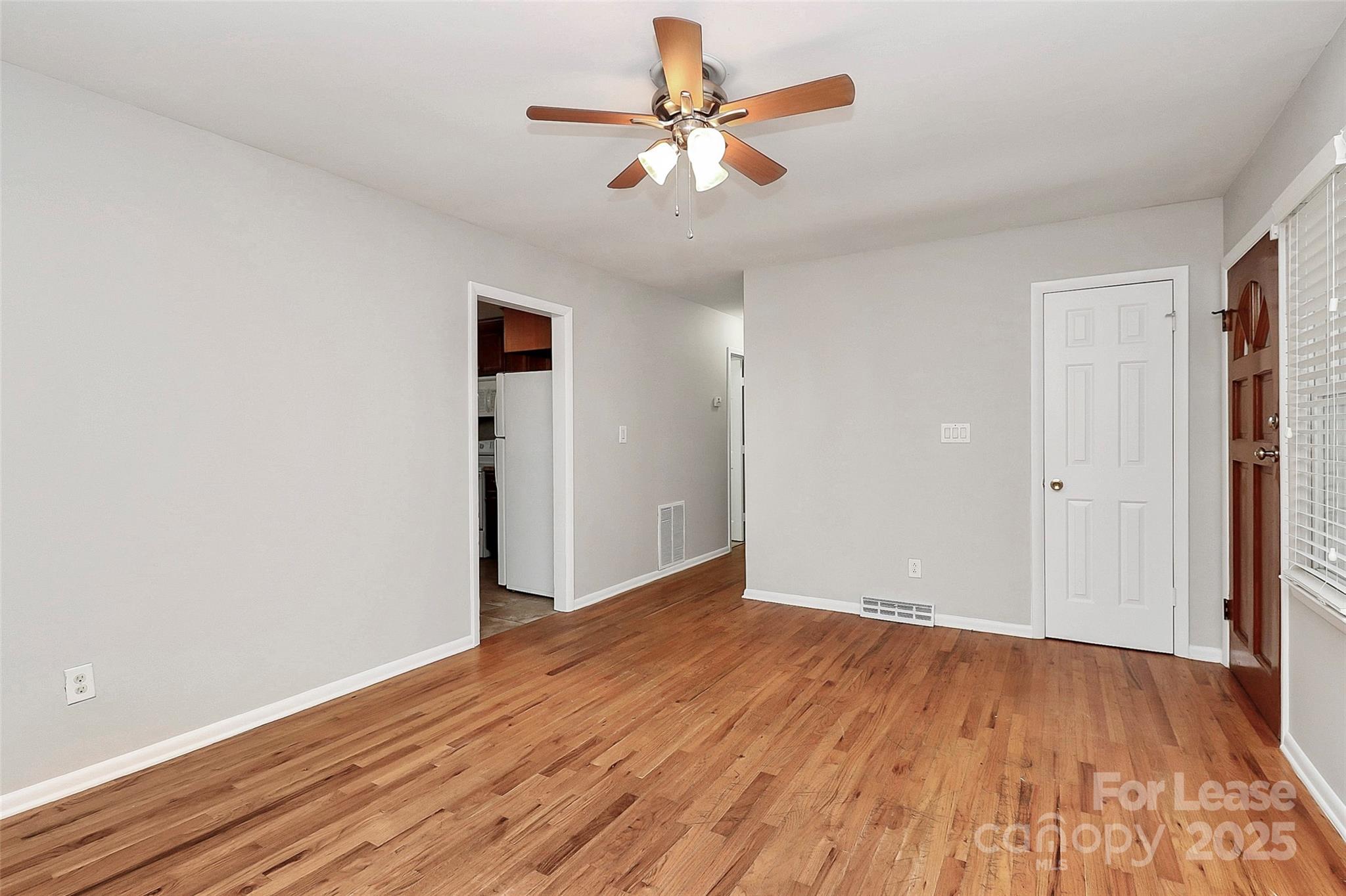 8911 Reames Road Charlotte, NC 28216 - Photo 8 of 31 an empty room with wooden floor and a ceiling fan
