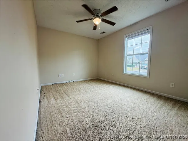 an empty room with windows and fan