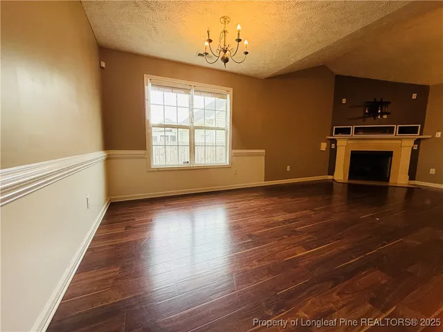 an empty room with wooden floor fireplace and windows