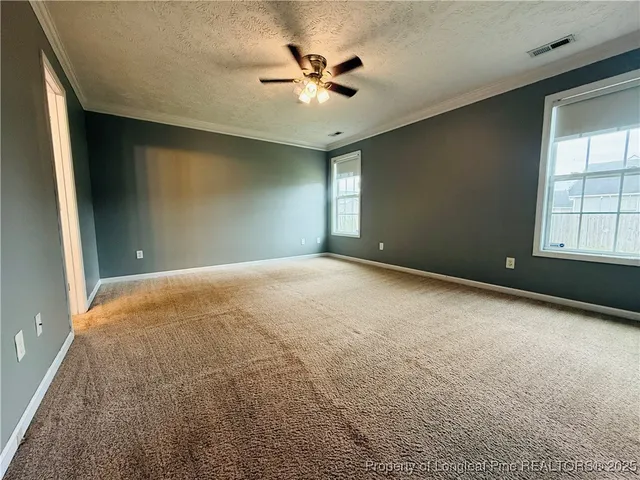 an empty room with windows and ceiling fan