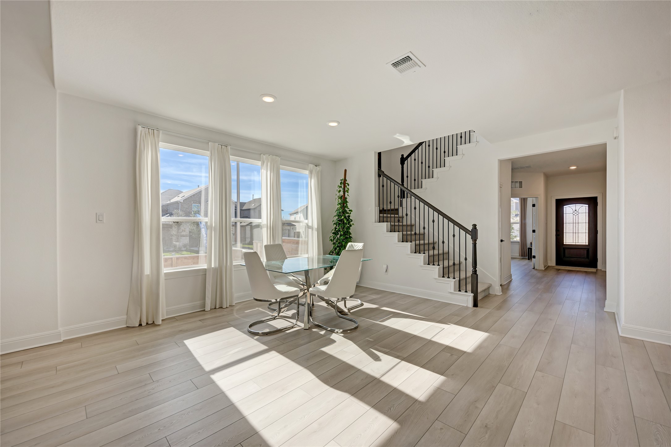 316 Regatta Trail Leander, TX 78641 - Photo 13 of 37 Bright open-concept space featuring wood-finish flooring, a contemporary staircase with iron balusters, three large windows, recessed lighting, and a paneled entry door with leaded glass accents
