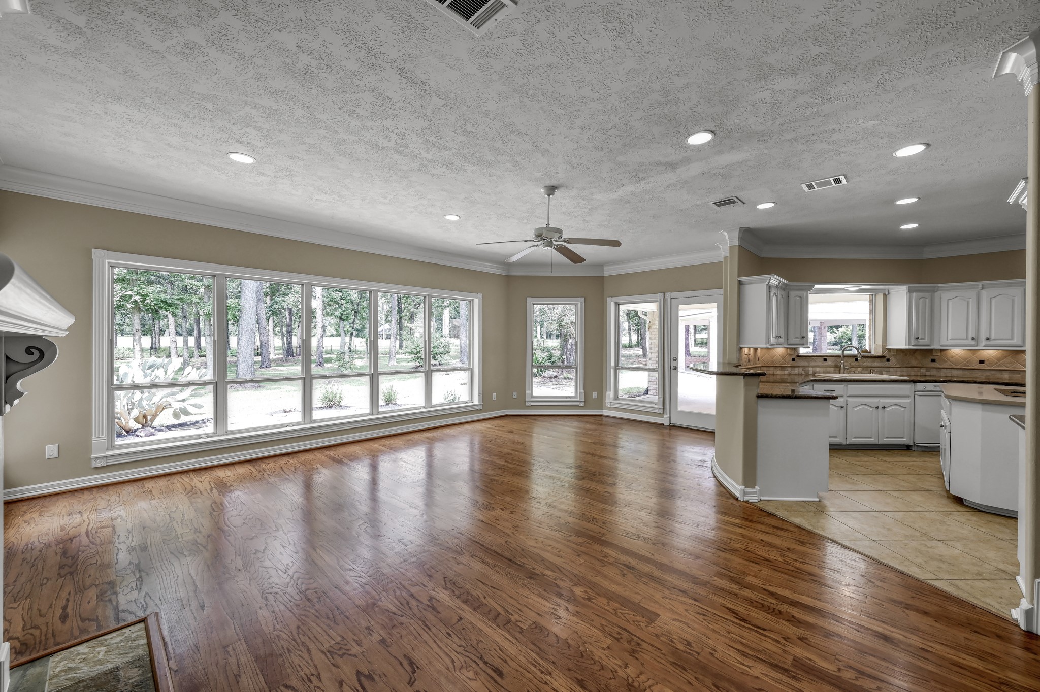 2205 Longmire Road Conroe, TX 77304 - Photo 10 of 49 This spacious, open-concept living area features beautiful hardwood floors and large windows offering serene views of your beautiful backyard. The adjacent kitchen is equipped with ample cabinetry, perfect for entertaining or family gatherings.