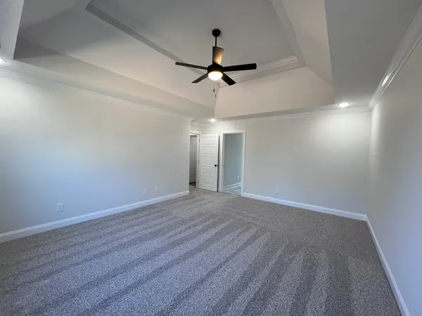 an empty room with chandelier fan and windows