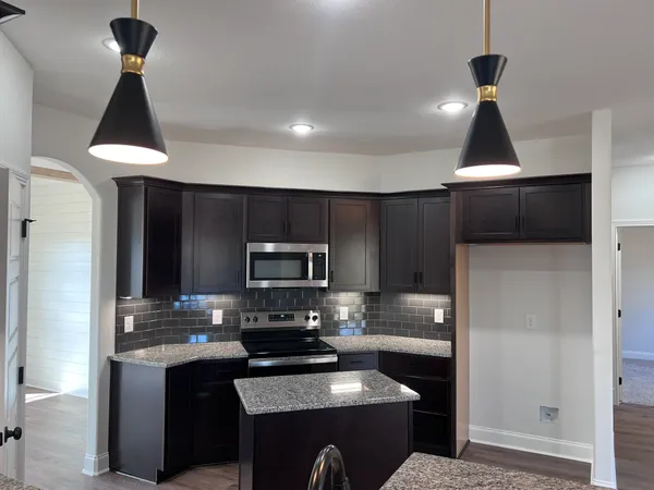 a kitchen with granite countertop kitchen island stainless steel appliances a sink stove and refrigerator