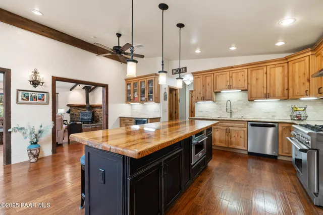 a kitchen with stainless steel appliances granite countertop a sink a stove and a wooden floors