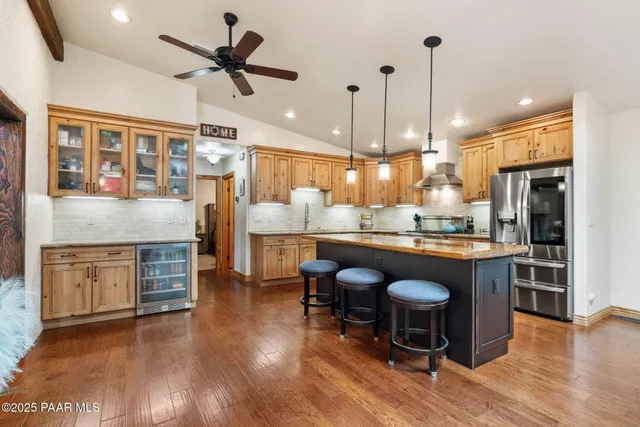 a kitchen with kitchen island granite countertop a stove a sink a refrigerator and a dining table with wooden floor
