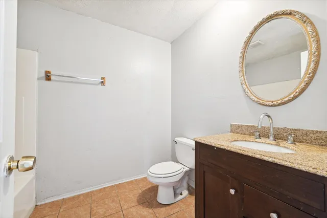 a bathroom with a granite countertop toilet a sink and a mirror