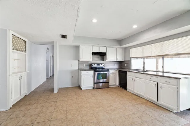 a kitchen with granite countertop white cabinets and stainless steel appliances