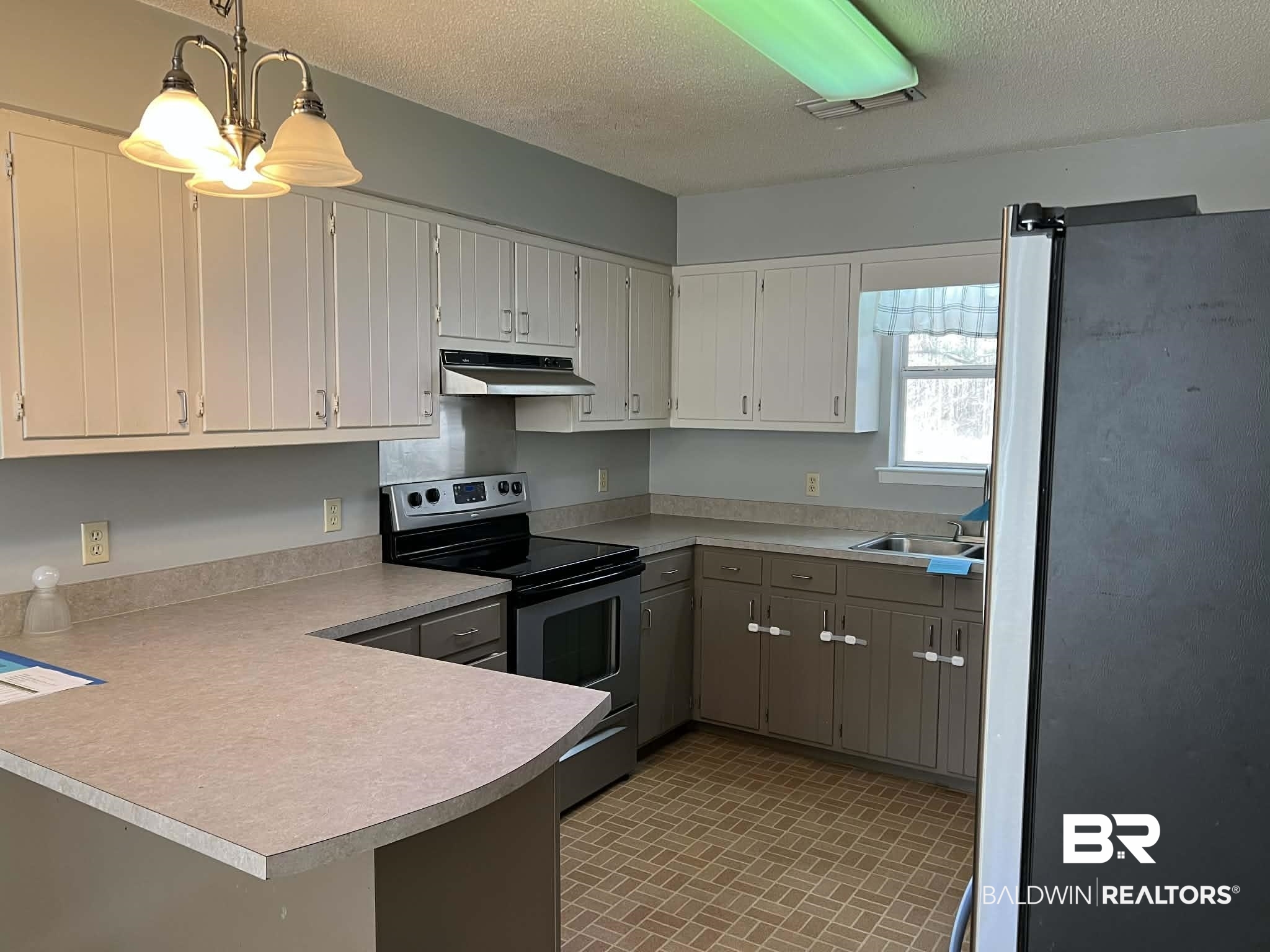 2391 Foshee Road Brewton, AL 36426 - Photo 2 of 14 Kitchen with appliances with stainless steel finishes, brick patterned flooring, white cabinets, a peninsula, and pendant lighting