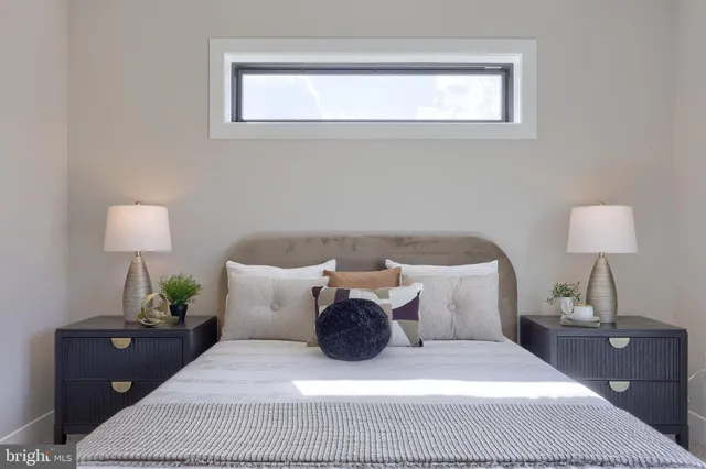 a spacious bedroom with a bed and a lamp on table