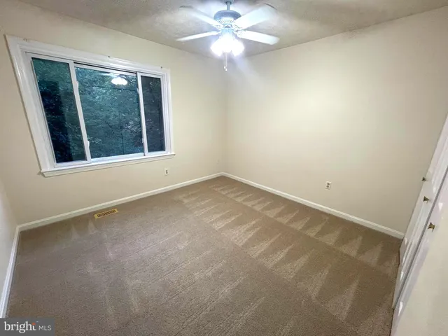 an empty room with a window and a fan