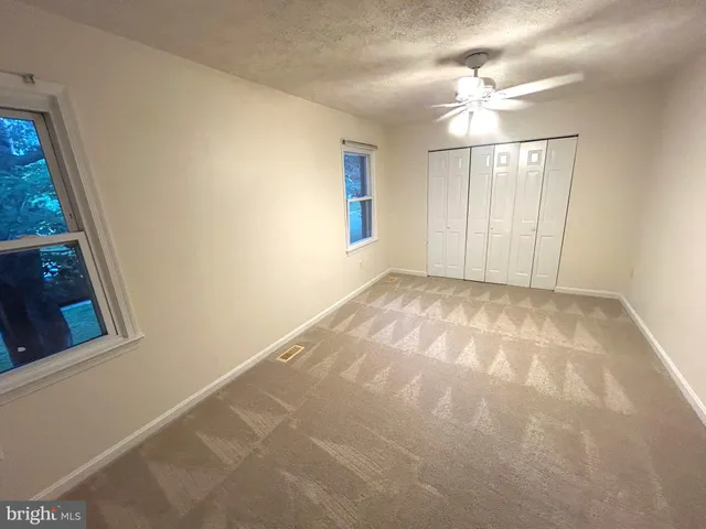 en empty room with windows and chandelier fan
