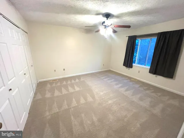 a view of an empty room with a chandelier fan