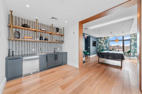 a living room with stainless steel appliances furniture a rug and a kitchen