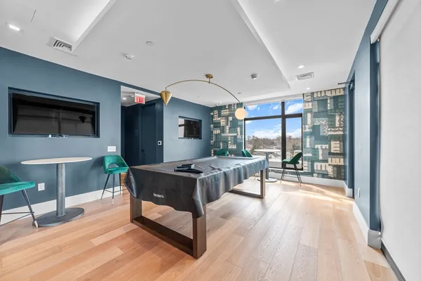 a living room with furniture a large window and wooden floor
