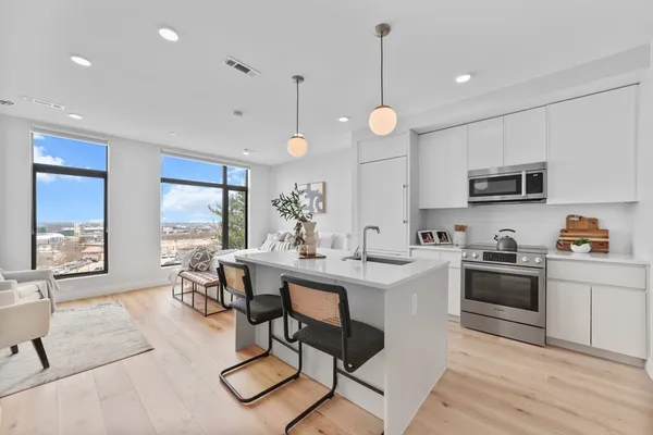 a open dining room with stainless steel appliances granite countertop a stove a sink dishwasher a dining table and chairs with wooden floor