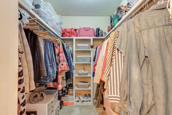 a view of walk in closet with clothes and shoes