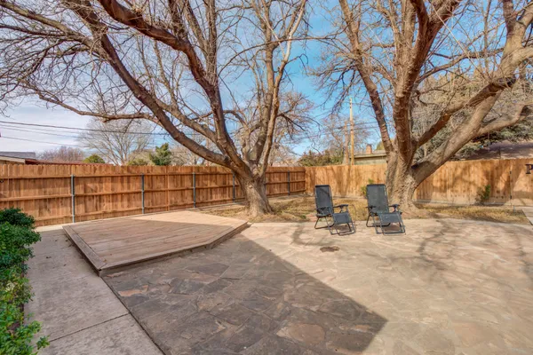 a backyard of a house with large trees and covered with snow