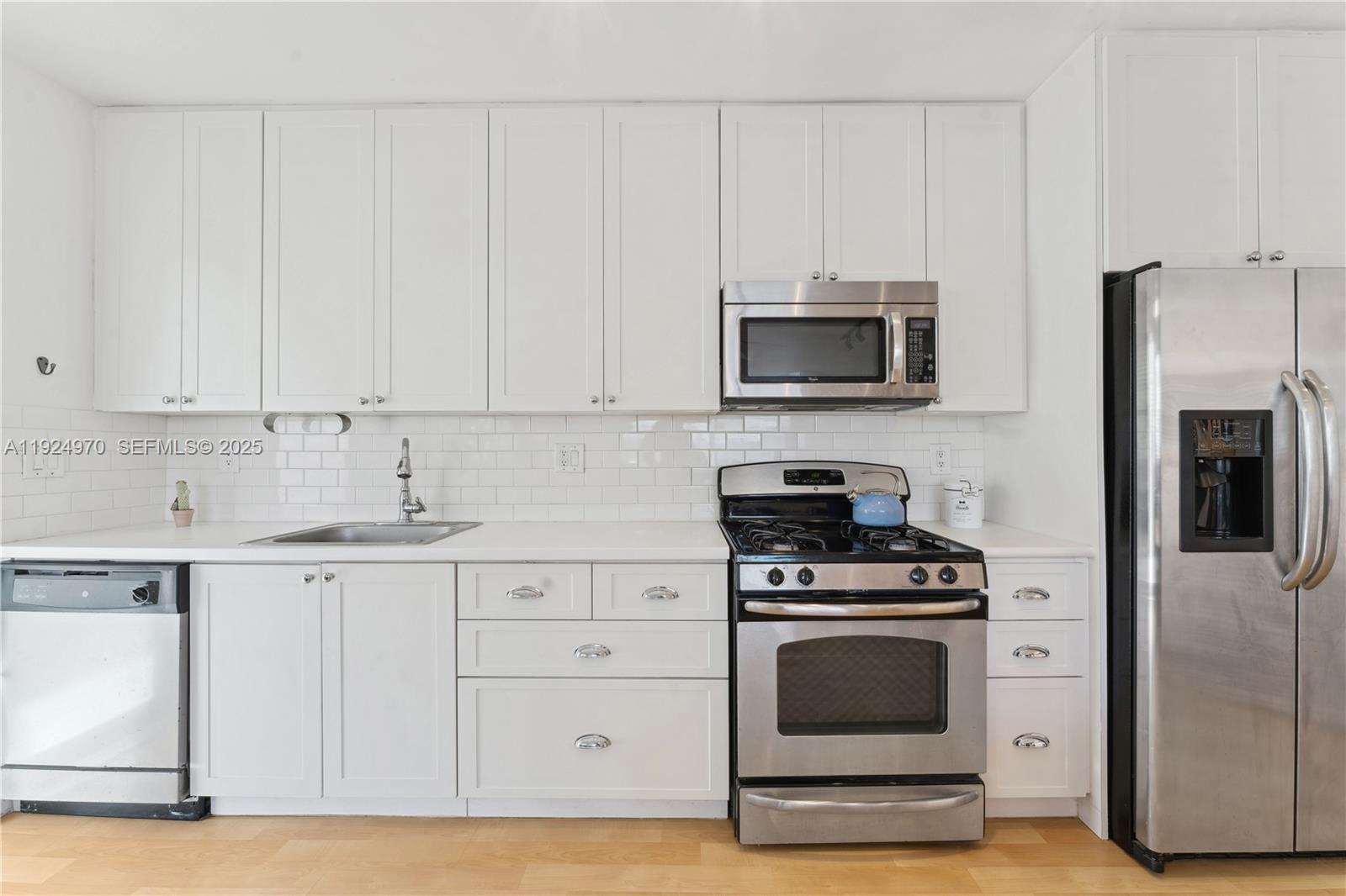 7440 Byron Avenue, Unit 1B Miami Beach, FL 33141 - Photo 8 of 16 a kitchen with granite countertop white cabinets and stainless steel appliances