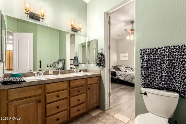 a en suite bathroom with a double vanity sink toilet mirror and shower