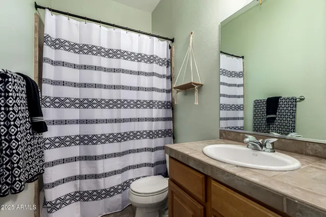 a bathroom with a granite countertop sink and a toilet