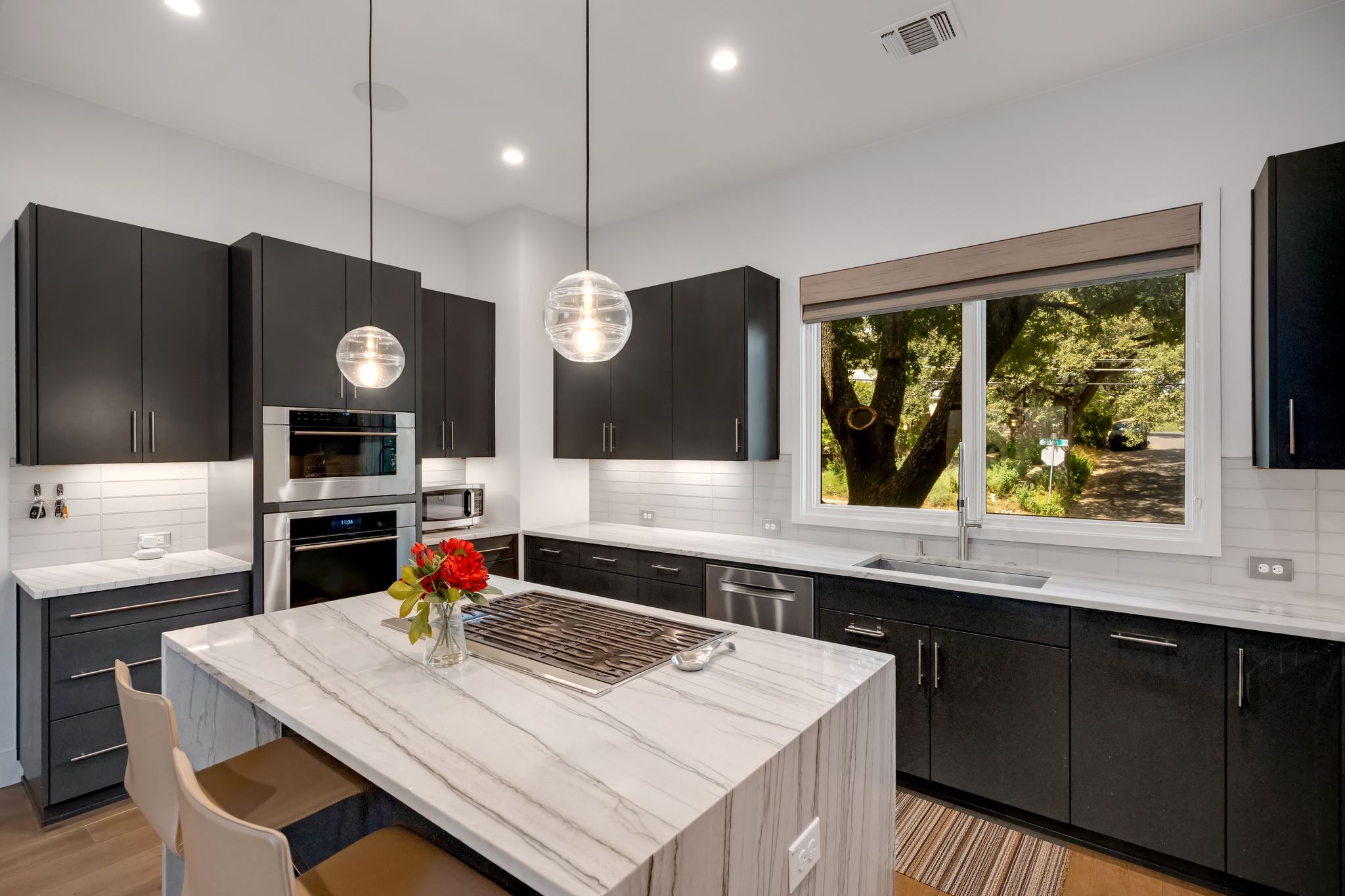 809 Bouldin Avenue Austin, TX 78704 - Photo 8 of 39 Kitchen with dark cabinetry, light stone countertops, pendant lighting, and tasteful backsplash