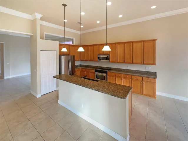 a kitchen with stainless steel appliances granite countertop a sink a oven and a wooden cabinets
