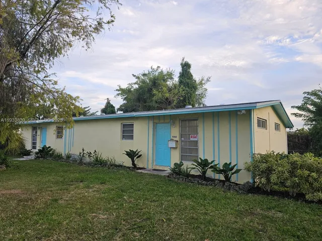 a backyard of a house with potted plants and large tree