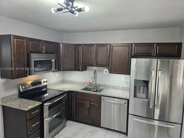 a kitchen with granite countertop a refrigerator stove and sink