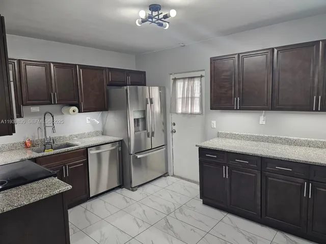 a kitchen with stainless steel appliances granite countertop a sink refrigerator and cabinets