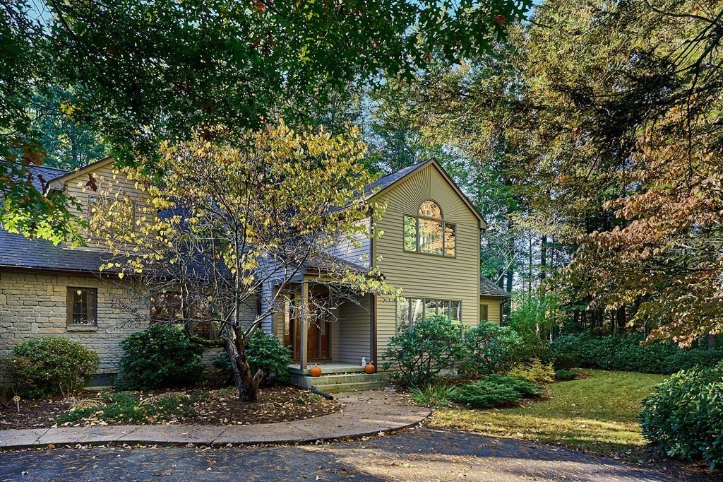 a front view of a house with a yard and large tree