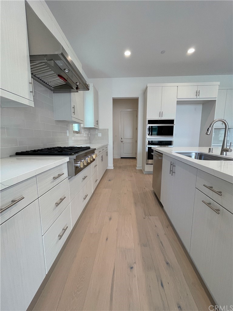 215 Sutters Mill Irvine, CA 92602 - Photo 18 of 57 a kitchen with stainless steel appliances a sink dishwasher stove refrigerator and cabinets with wooden floor