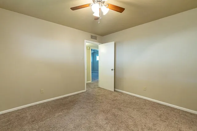 an empty room with a chandelier fan and windows