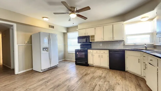 a kitchen with stainless steel appliances granite countertop a refrigerator a sink dishwasher a stove with wooden cabinets and floors