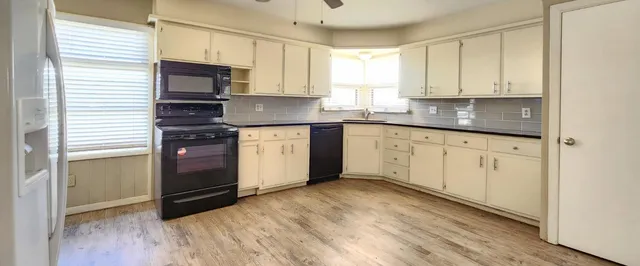 a kitchen with granite countertop white cabinets stainless steel appliances a sink and a window