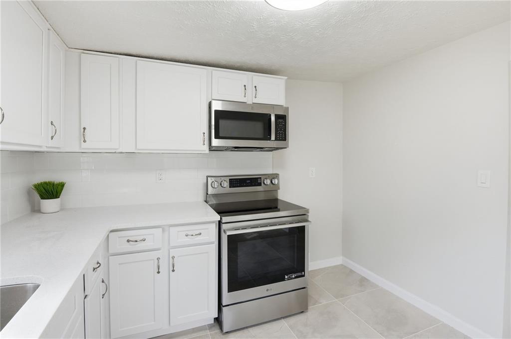 1780 Wynn Lake Road Alto, GA 30510 - Photo 12 of 30 a kitchen with granite countertop white cabinets and stainless steel appliances