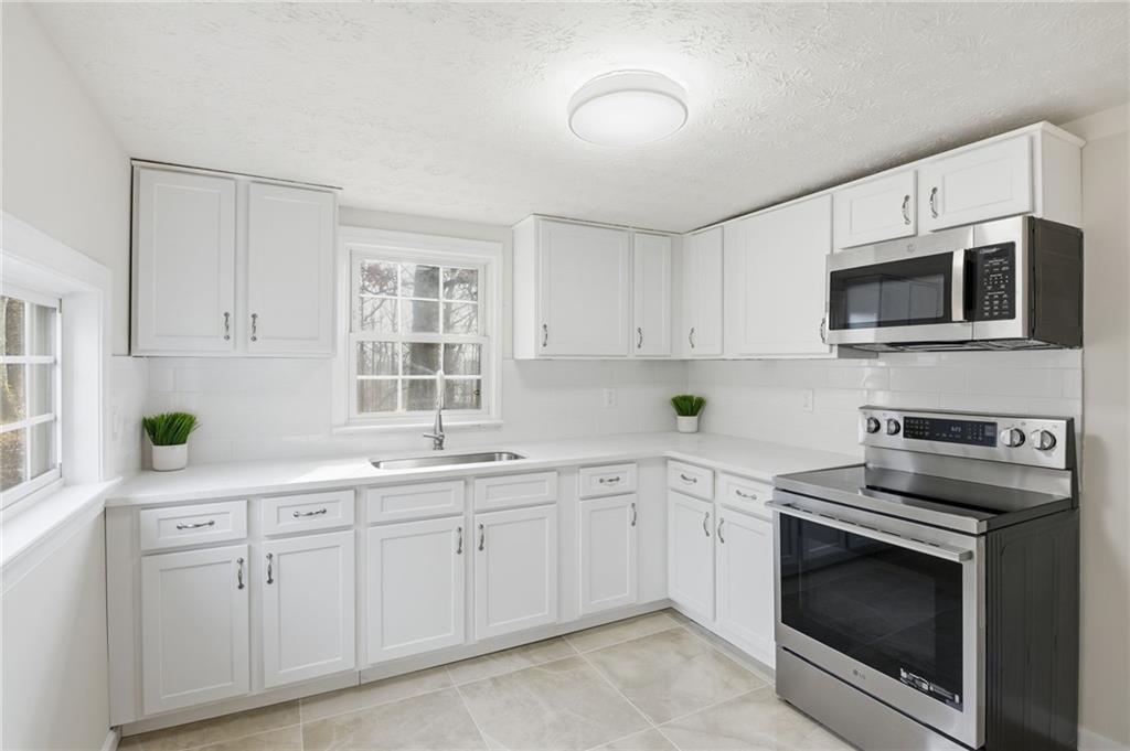 1780 Wynn Lake Road Alto, GA 30510 - Photo 10 of 30 a kitchen with white cabinets stainless steel appliances and sink