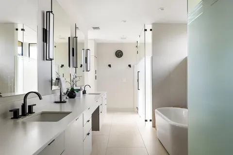a bathroom with a double vanity sink a toilet and a tub