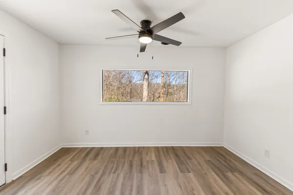 an empty room with wooden floor and ceiling fan