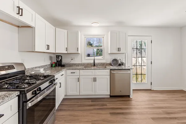a kitchen with granite countertop a stove top oven sink and cabinets