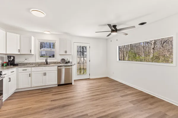 a kitchen with granite countertop white cabinets a sink a window and stainless steel appliances