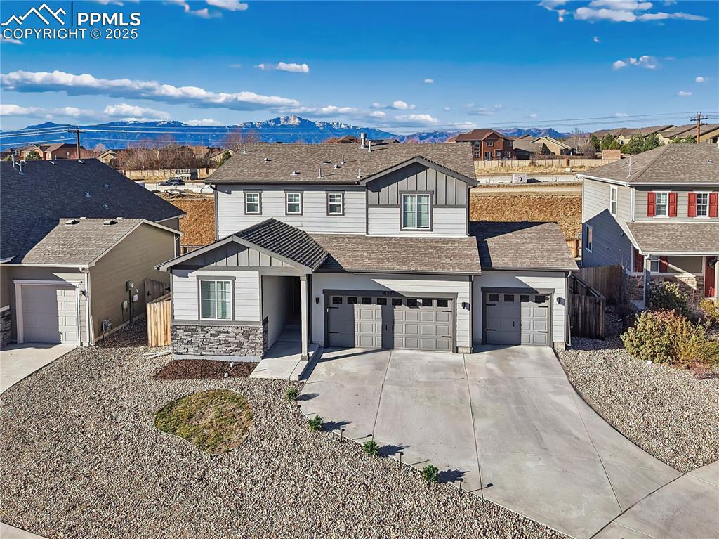 exterior with a true 3-car garage and low-maintenance landscaping, set against scenic mountain views of Pikes Peak