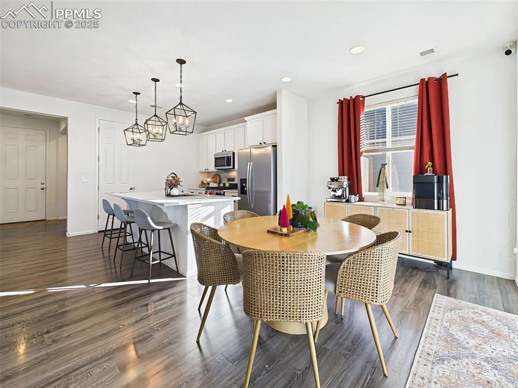 6272 Anders Ridge Lane Colorado Springs, CO 80927 - Photo 11 of 50 A full view of the open-plan kitchen and dining areas, where large windows, pendant lighting, and stylish flooring come together in a clean, cohesive space.