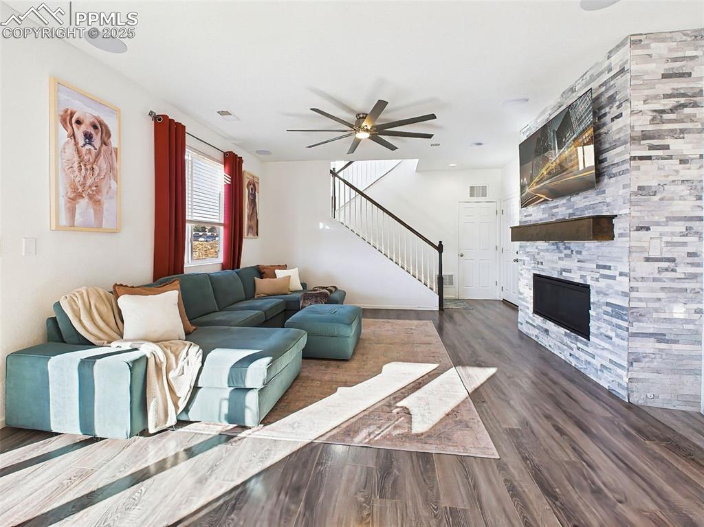 6272 Anders Ridge Lane Colorado Springs, CO 80927 - Photo 20 of 50 Bright and spacious living area anchored by a stacked stone fireplace with a drywall finish and wood mantel, creating a contemporary focal point.
