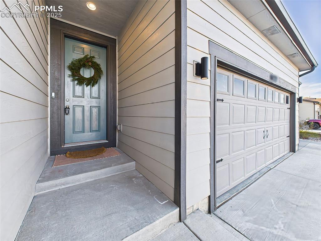 6272 Anders Ridge Lane Colorado Springs, CO 80927 - Photo 2 of 50 Covered front entry paired with upgraded 3-car garage featuring added windows, service door, and upgraded exterior lighting.