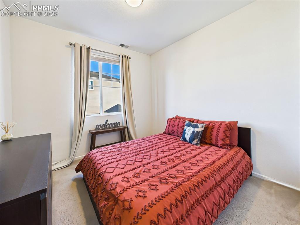 6272 Anders Ridge Lane Colorado Springs, CO 80927 - Photo 22 of 50 Versatile main-floor bedroom with carpeted flooring and a large window—ideal as a guest suite, office, or multi-gen option.
