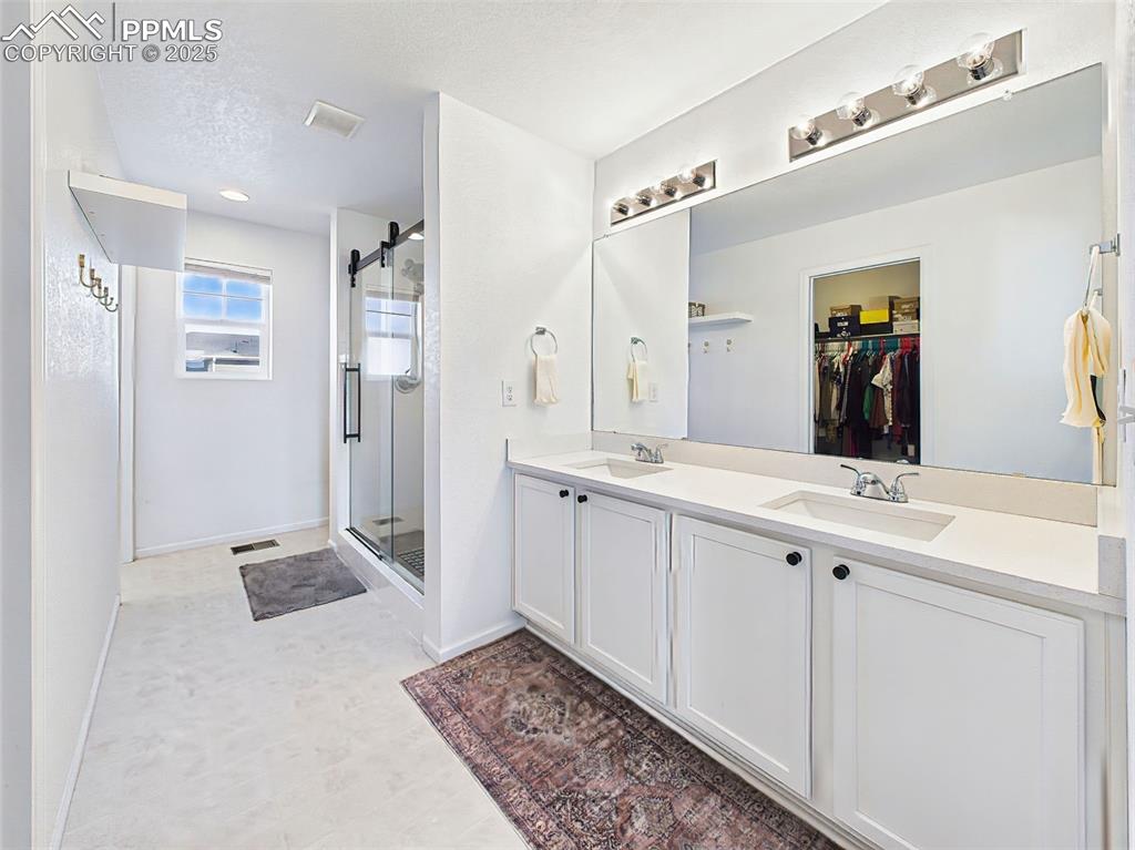 6272 Anders Ridge Lane Colorado Springs, CO 80927 - Photo 30 of 50 Spa-inspired primary bathroom with quartz countertops, dual sinks, upgraded mud-set shower, and walk-in closet access.