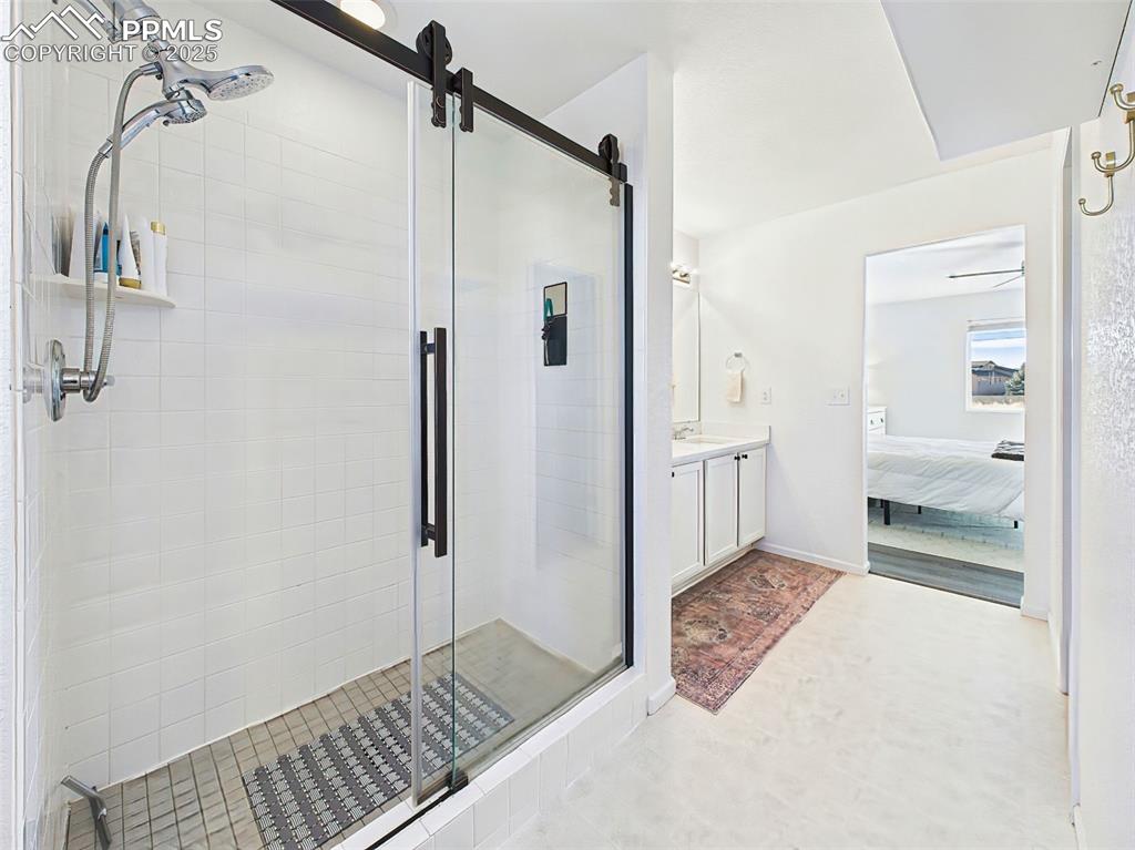 6272 Anders Ridge Lane Colorado Springs, CO 80927 - Photo 32 of 50 The oversized walk-in shower boasts a seamless glass enclosure with matte black barn-door hardware and a showerhead system, offering both style and functionality.