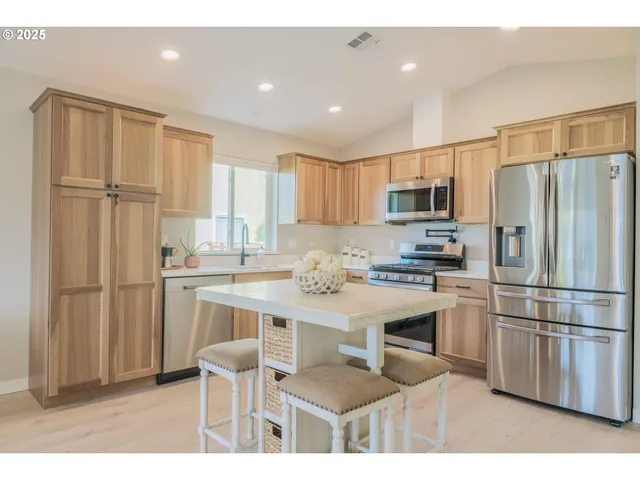 a kitchen with stainless steel appliances granite countertop a refrigerator a stove a sink and a refrigerator